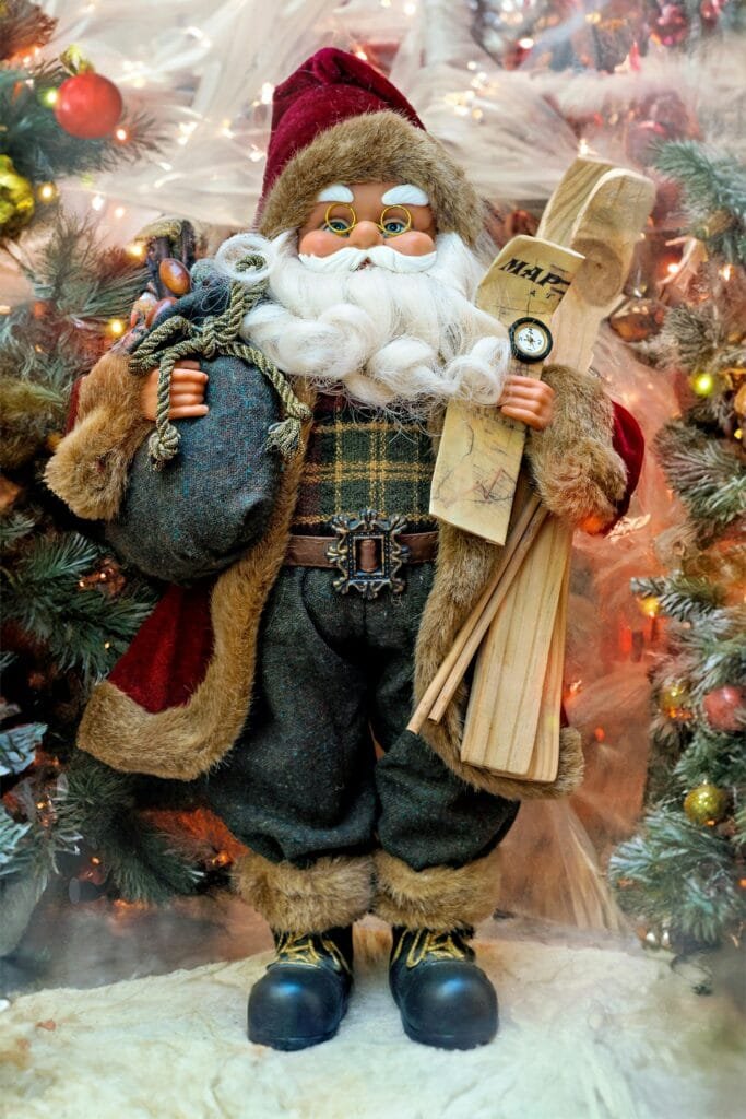 Charming Santa figurine with skis in a cozy Christmas scene, surrounded by lights and Christmas tree.