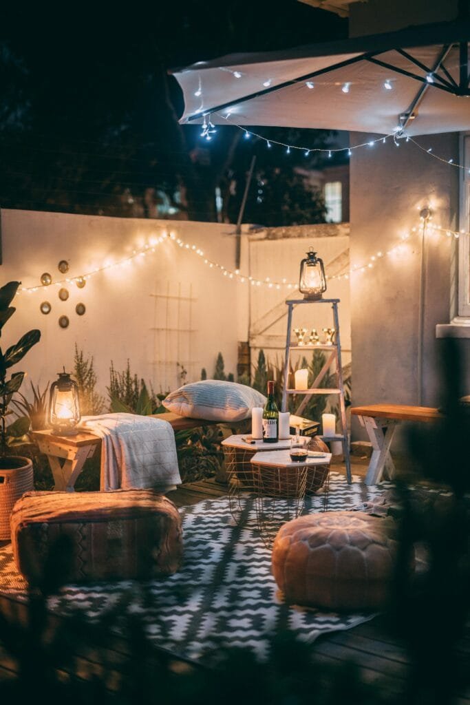 Warmly lit outdoor patio with cozy seating, lanterns, and decorative lights.