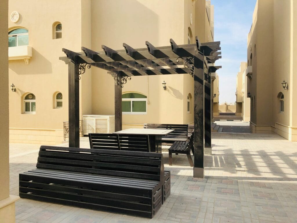 Modern outdoor seating area in an Abu Dhabi alley, featuring pergola and benches.