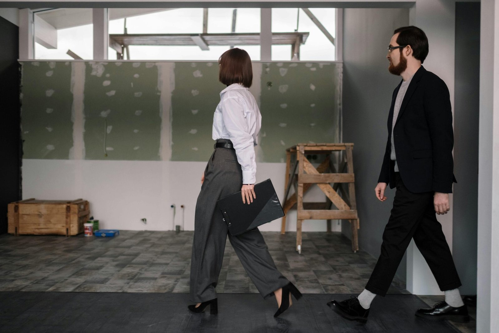 Businessman and businesswoman reviewing office construction progress indoors.